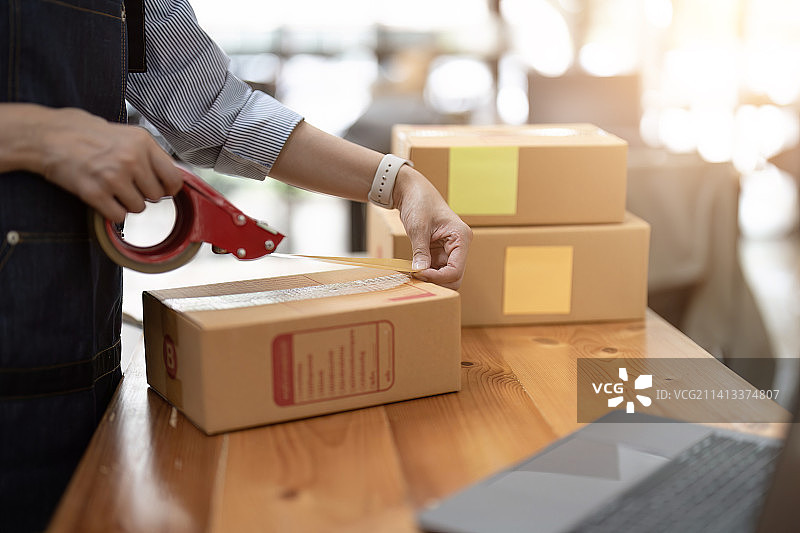 小型创业企业，年轻女性自由职业者打包货箱图片素材