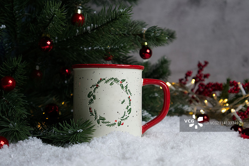 圣诞节附近，可爱的马克杯摆放在洒满雪的桌子上图片素材