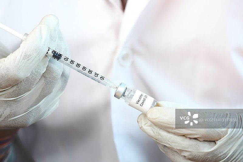 戴蓝色乳胶手套的手用注射器抽取药物图片素材