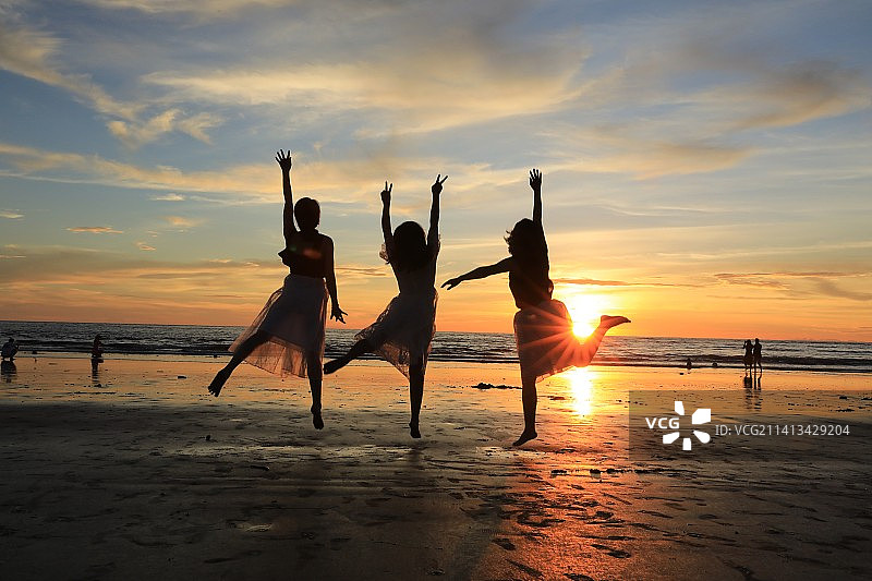 夕阳下海滩上的三个女人图片素材