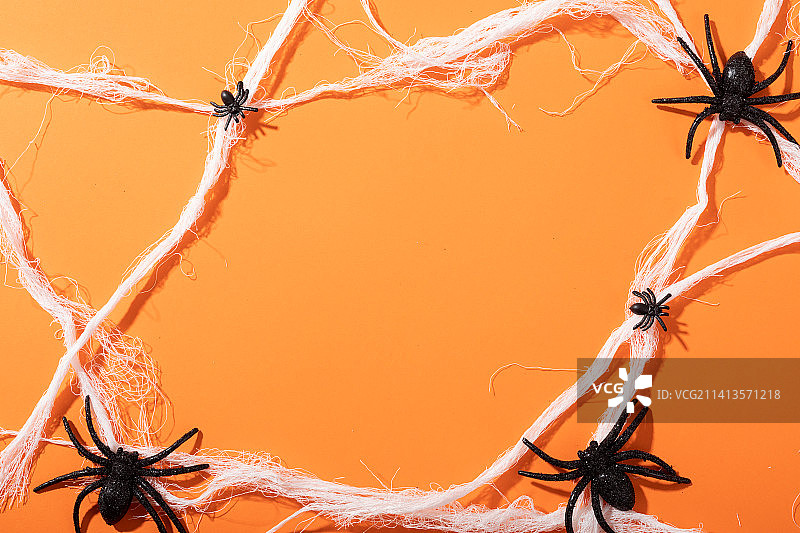 多个蜘蛛玩具形成蜘蛛网，橙色背景图片素材