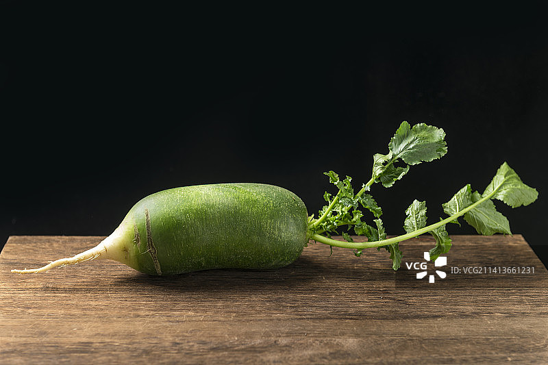 青萝卜摆放在木桌面背景上特写图片素材