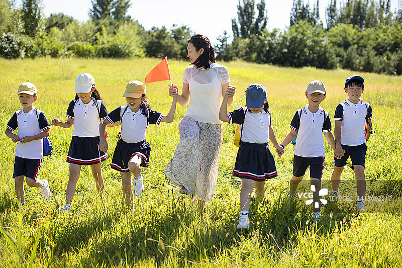 快乐的老师带领小学生春游图片素材