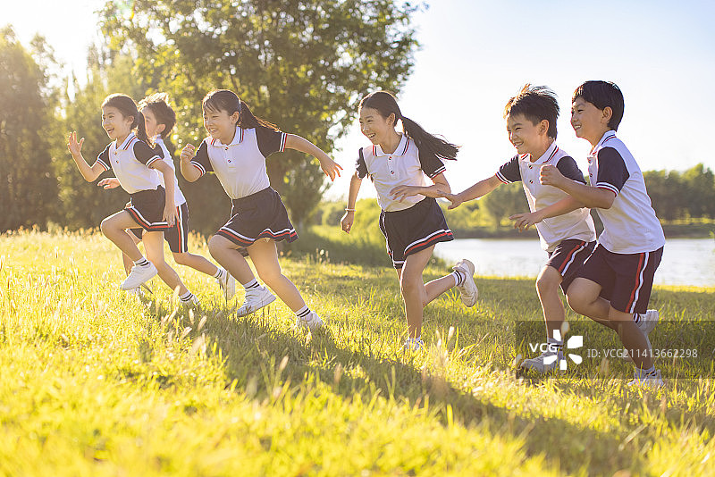 快乐的小学生在草地上奔跑图片素材