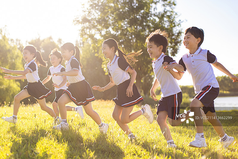快乐的小学生在草地上奔跑图片素材