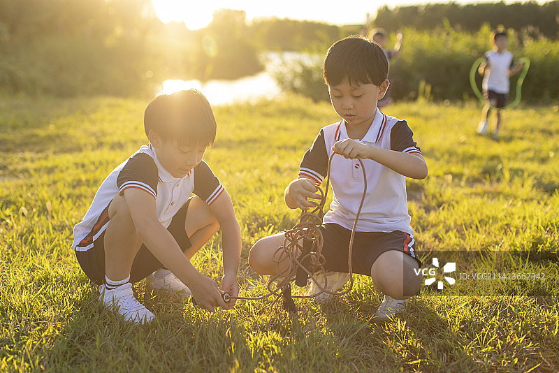 快乐的小学生在草地上玩图片素材