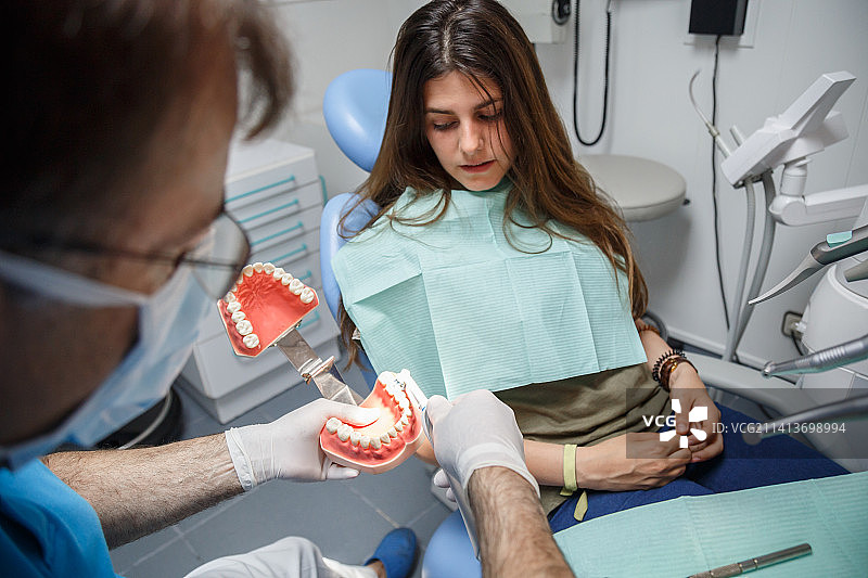 牙医向顾客展示牙齿清洁技术，西班牙马德里图片素材