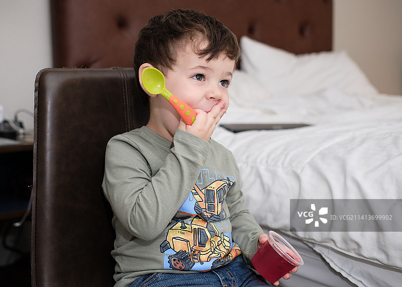 在纽约美国酒店房间里吃零食和看电视的可爱小男孩图片素材