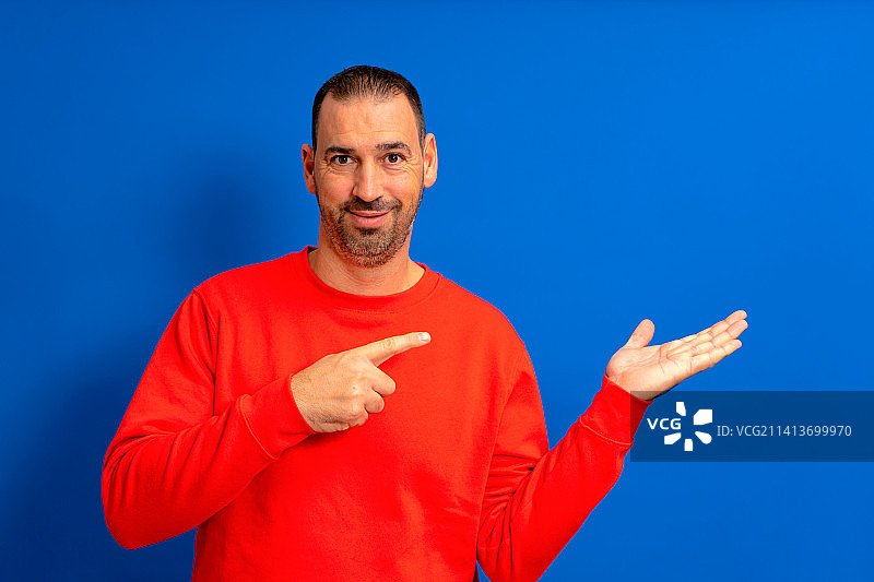 快乐的络腮胡男人指着手掌上的东西图片素材