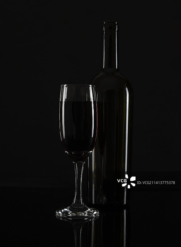 黑色桌上的高脚杯红酒和酒瓶图片素材