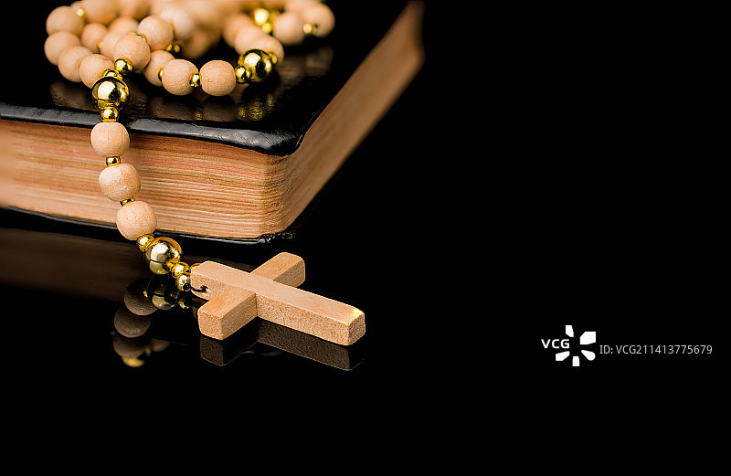 黑色背景下的木制十字架、圣经和念珠特写，英国图片素材