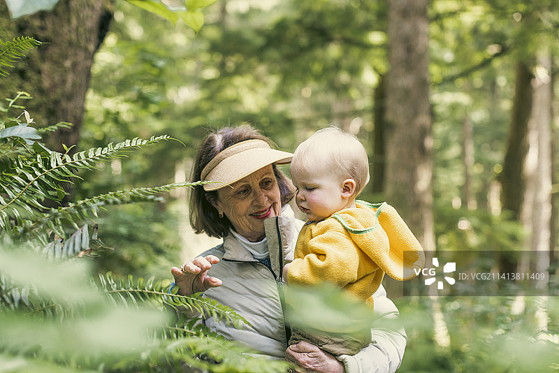 祖母抱着小宝宝在雨林中徒步旅行图片素材