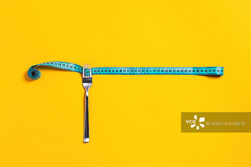饮食理念，黄色背景上的银叉卷尺图片素材