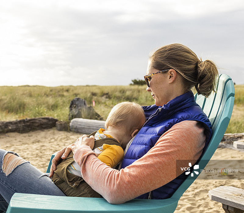 一位母亲在太平洋的沙丘上给小宝宝喂母乳。图片素材