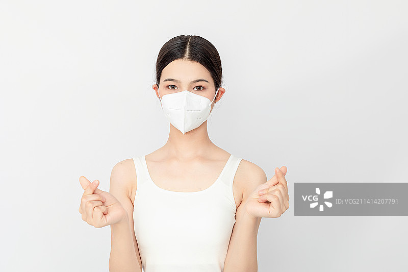一名戴KN95口罩的亚洲年轻女性比心手势图片素材