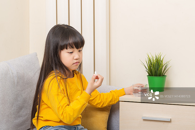 一个居家喝水吃药的亚洲小女孩图片素材