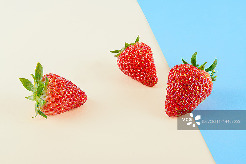 新鲜的草莓孤立在蓝色与黄色背景上图片素材
