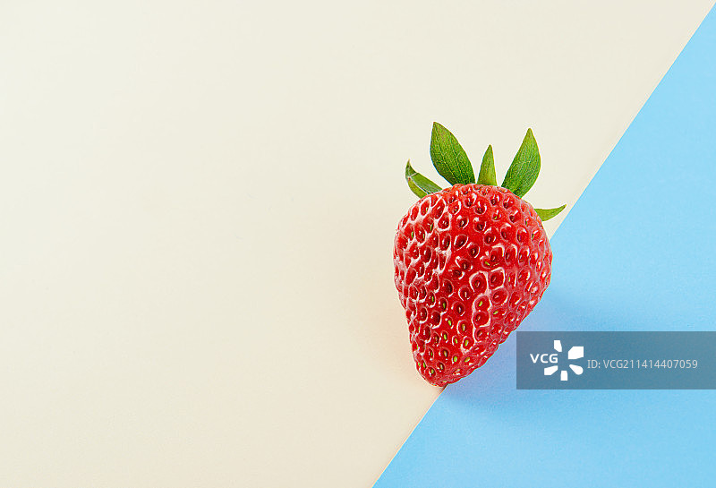 新鲜的草莓孤立在蓝色与黄色背景上图片素材