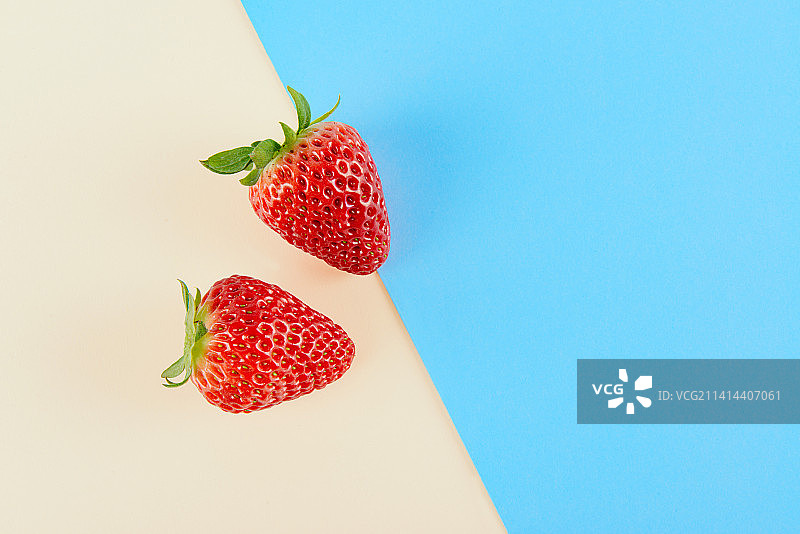 新鲜的草莓孤立在蓝色与黄色背景上图片素材