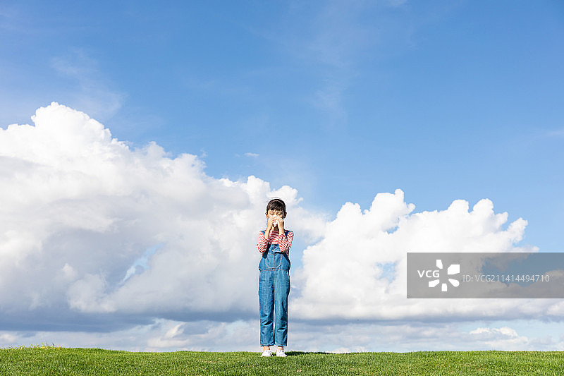 蓝天白云下一个中国小女孩在用纸巾擦鼻子图片素材