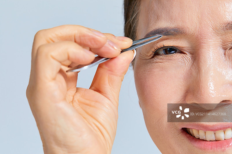 50、60年代老年妇女用眉毛镊子拔眉毛图片素材