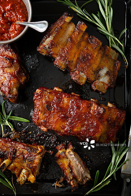 黑色表面上带有红色酱汁的烧烤烟熏排骨的俯视照片，乌克兰图片素材
