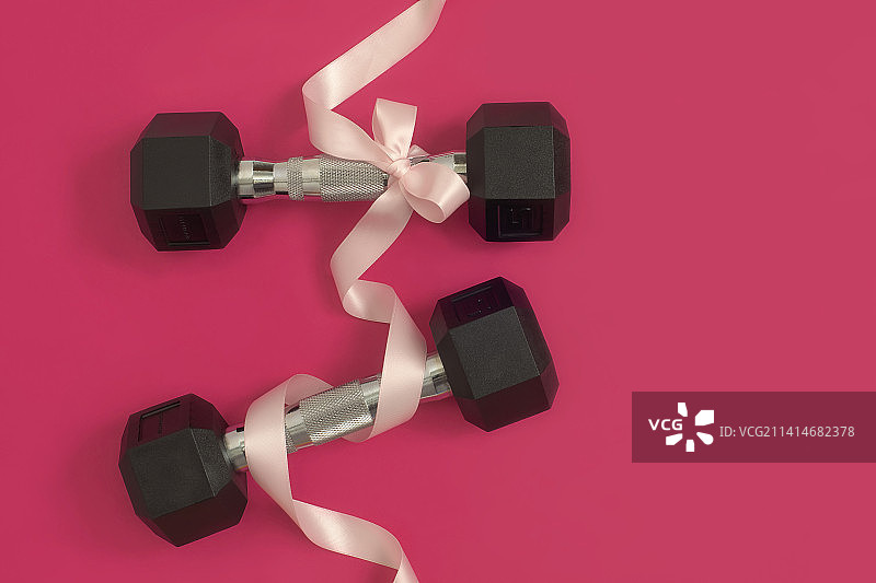 粉色背景上的蝴蝶结哑铃图片素材
