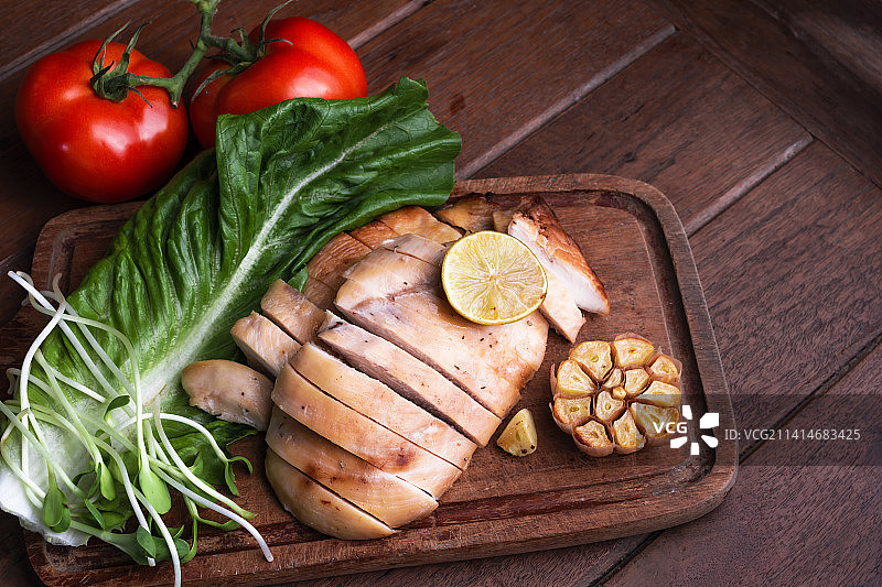 木质背景砧板上的烤鸡肉蔬菜图片素材