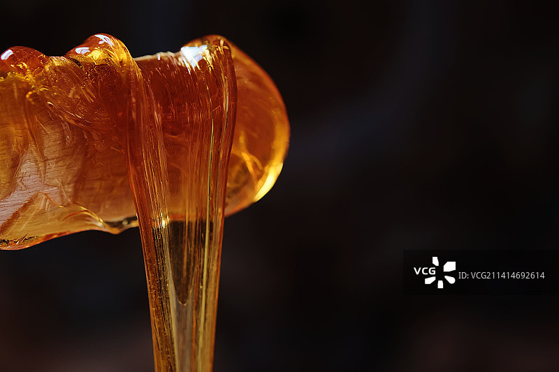 深色背景下木棍上滴落的糖浆图片素材