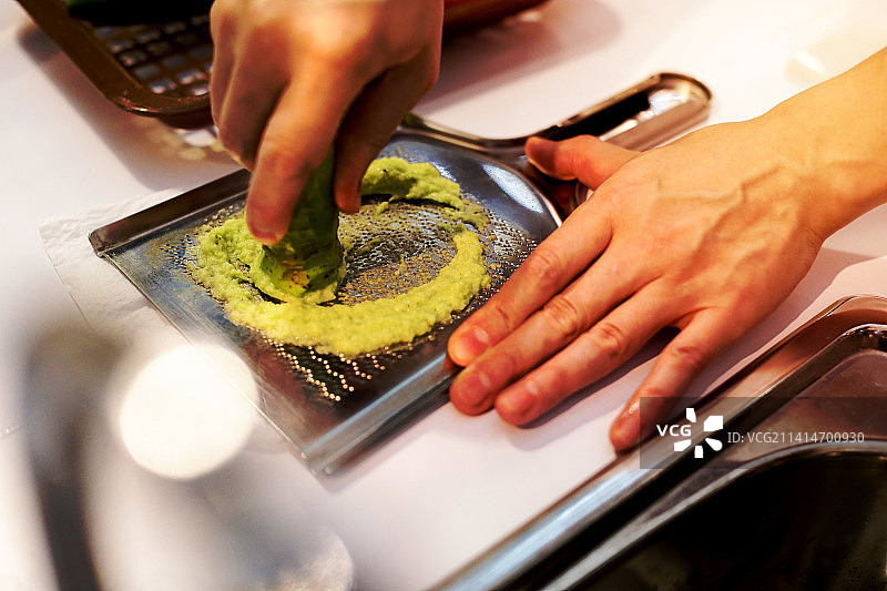 寿司厨师磨新鲜山葵，为握寿司准备新鲜山葵根图片素材