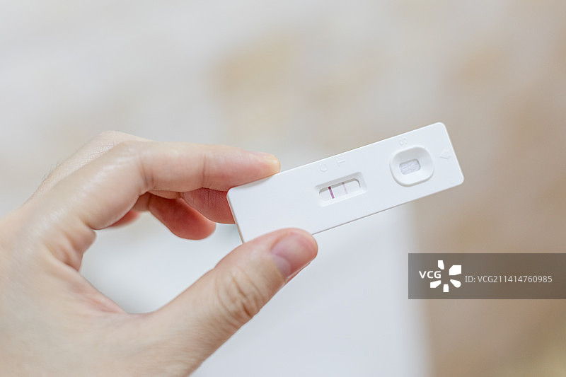 女性手拿着显示阳性的快速检测卡验孕或抗原检测图片素材