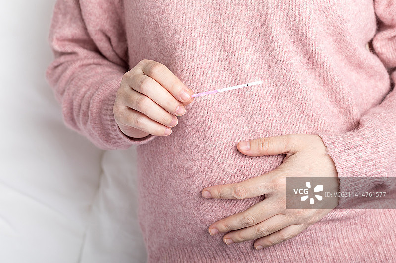 一个年轻女子手拿着验孕棒图片素材