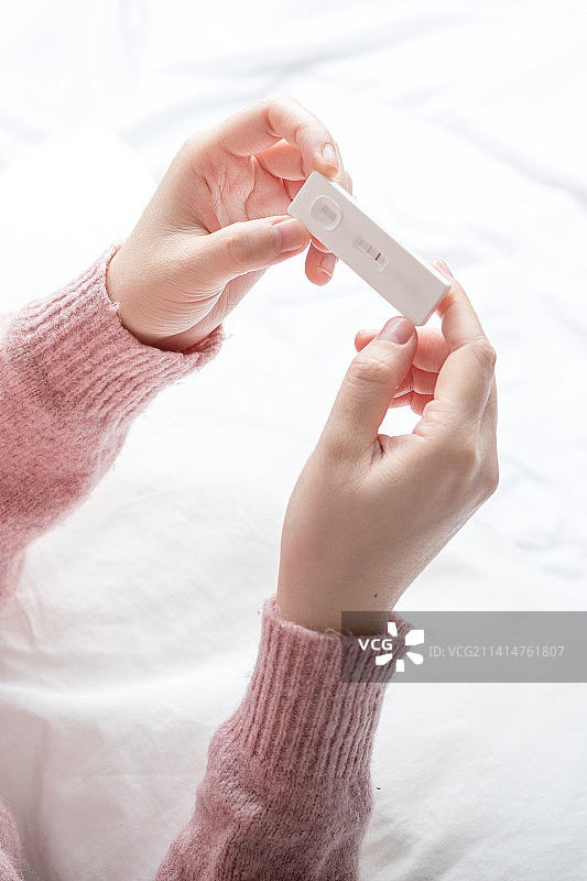 女性手拿着显示阳性的快速检测卡验孕或抗原检测图片素材