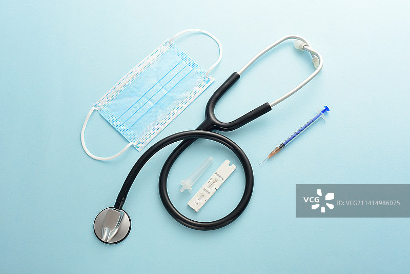 蓝色背景上的核酸检测抗原检测试剂和听诊器口罩注射器图片素材