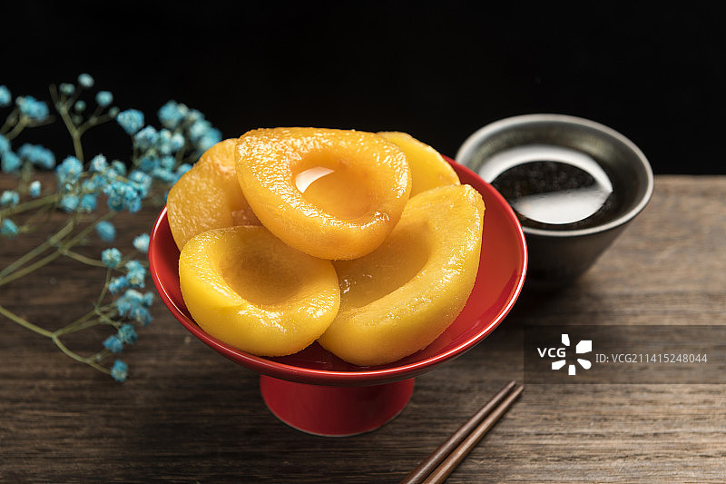 一盘黄桃罐头摆放在木桌面上特写图片素材