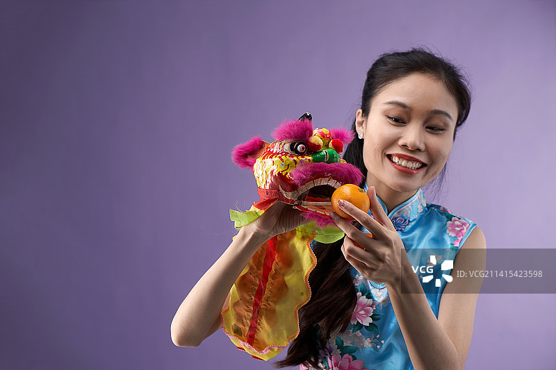身穿旗袍的女人与舞狮玩具的乐趣，马来西亚图片素材