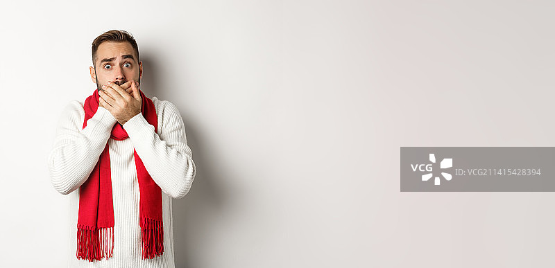 冬季假日和购物概念：惊恐的男子倒吸一口气，捂住嘴巴图片素材