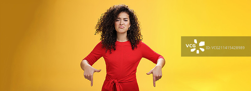 穿着红色连衣裙的阴沉、失望、可爱的卷发女子图片素材