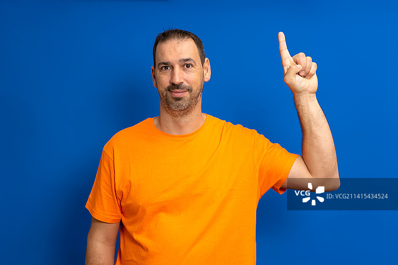 穿着橙色T恤的有洞察力的聪明白人男人图片素材
