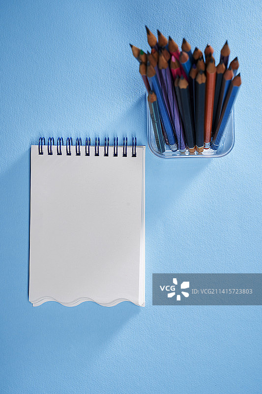 蓝色背景下的空白笔记本和铅笔，马来西亚图片素材