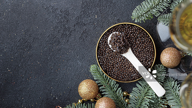 圣诞装饰黑色餐桌上的黑色鱼子酱开胃菜，芬兰图片素材
