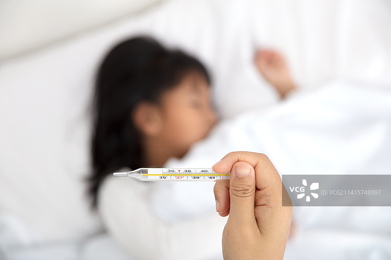发烧的孩子躺在床上温度计图片素材
