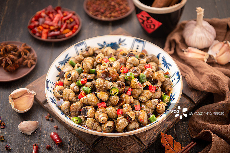 中式木纹桌上的爆炒田螺图片素材