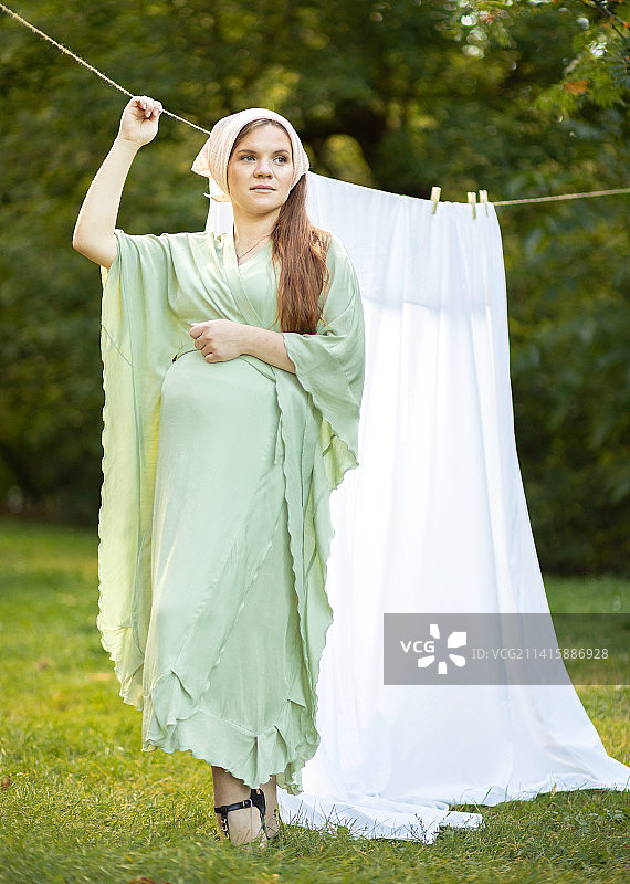 站在晾衣绳旁的大肚子孕妇图片素材