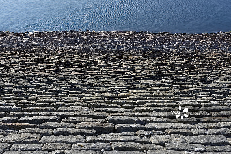 抽象的堤坝墙，俯瞰深蓝色水域，阳光明媚的石头，英国谢菲尔德Redmires水库图片素材