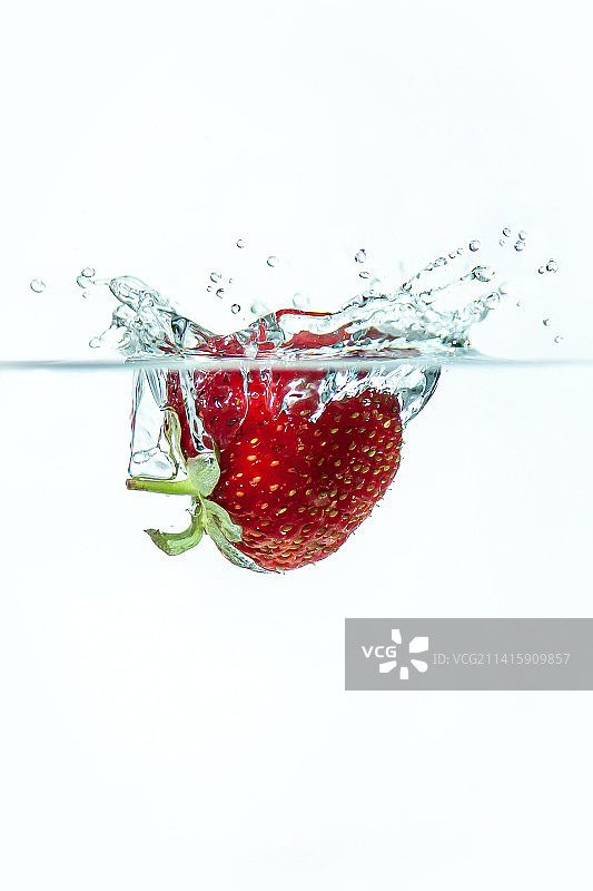 印尼，白色背景下草莓溅入水中的特写图片素材