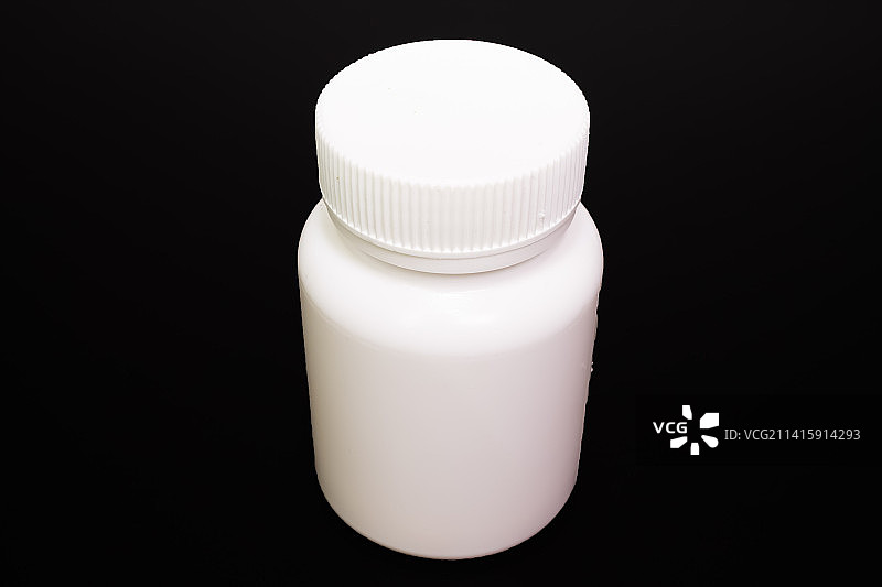 黑色背景上带白色盖子的白色空小瓶图片素材