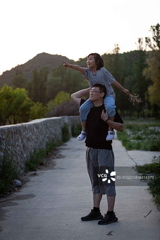 父亲肩膀扛着女儿眺望远方图片素材