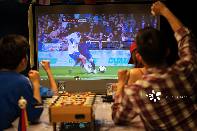 年轻朋友一起从投影屏幕上看足球比赛图片素材