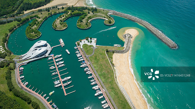 航拍石梅湾游艇码头和建筑，透明蓝绿色海水清澈见底，游艇在海面穿行画出白色的轨迹图片素材